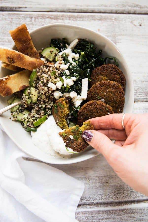 scooping tzatziki with a piece of falafel