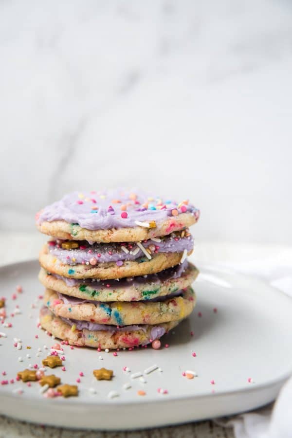 stacked sprinkle cookies frosting with purple frosting