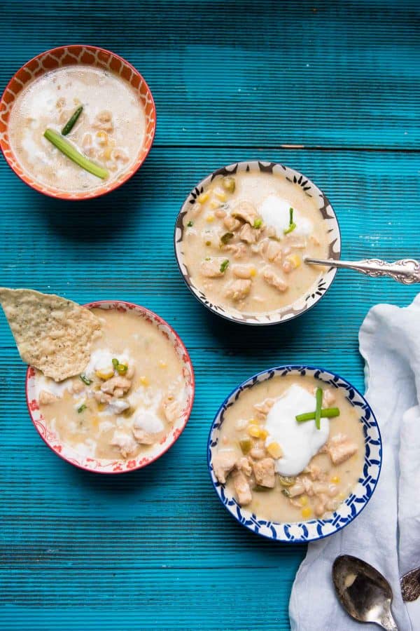 four bowls of white chicken chili topped with sour cream