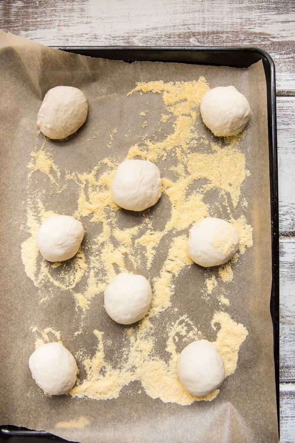 overhead angle of raw dough balls on a baking sheet with cornmeal