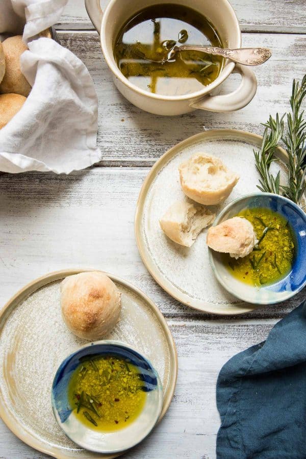 bowls of dipping oil on plates with fresh rolls