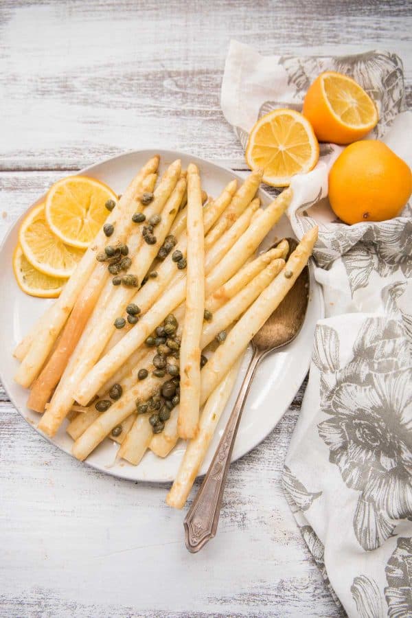 white asparagus with piccata sauce on a plate