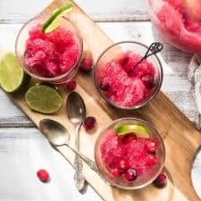 cranberry vodka slushies in glasses on a wood board
