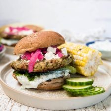 side angle of burger with cucumbers and corn