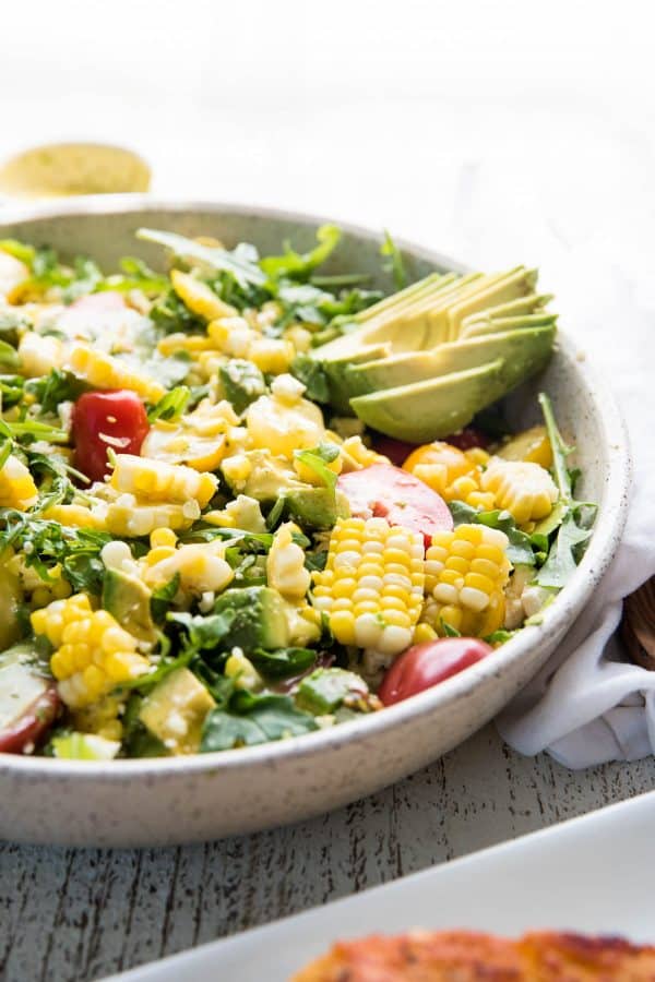 side angle of a platter full of summer salad ingredients and sliced avocado