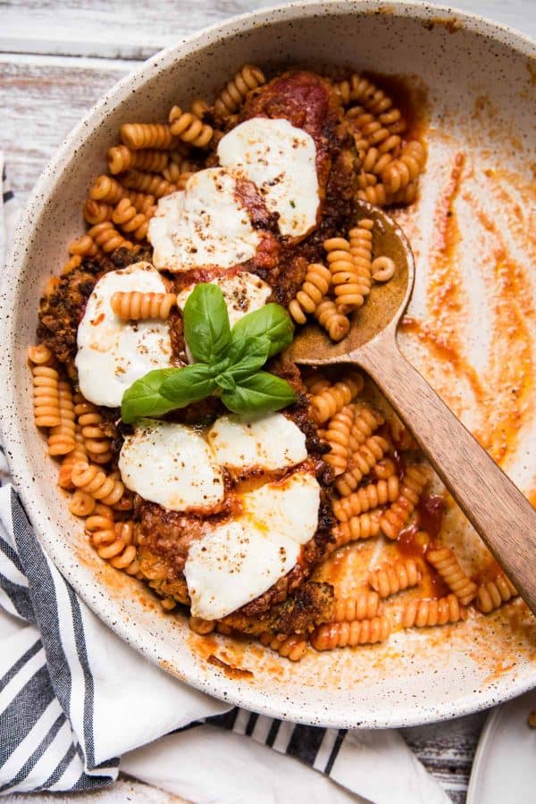 serving bowl of pasta and chicken with serving spoon scooping out pasta