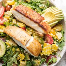 close up of pan seared halibut over corn and avocado salad