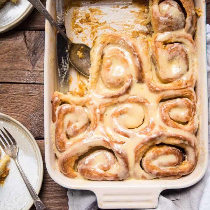 spoon scooping out cinnamon roll out of baking dish