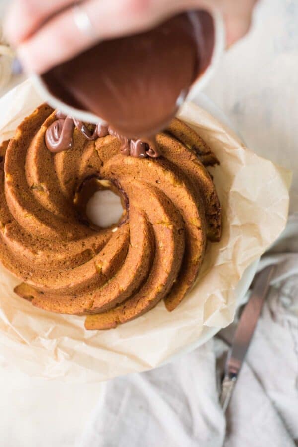 chocolate glaze pouring on top of a cake on parchment paper