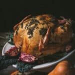 side angle of roasted turkey on a serving platter with pomegranates