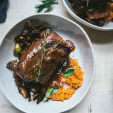 overhead of short ribs in wine sauce over sweet potato mash in a bowl