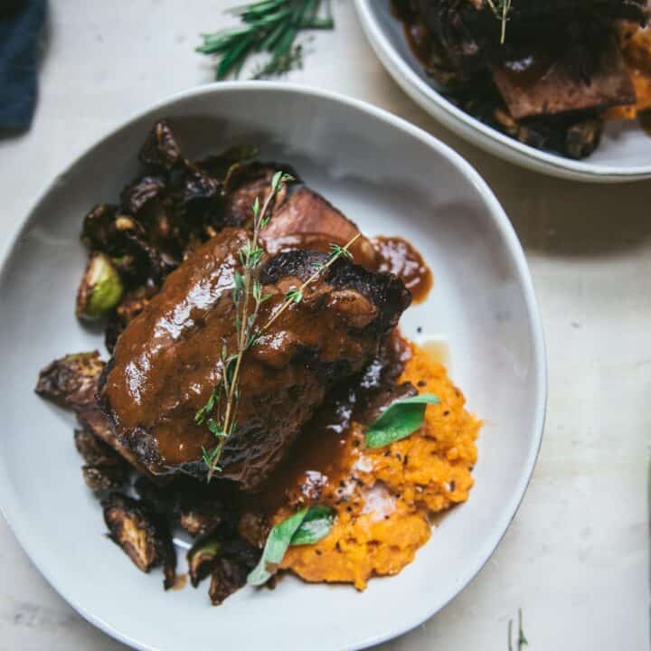 overhead of short ribs in wine sauce over sweet potato mash in a bowl