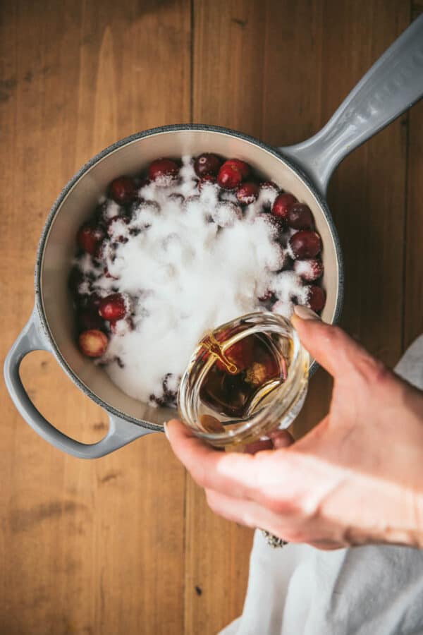 pouring bourbon into a pian with cranberries and sugar