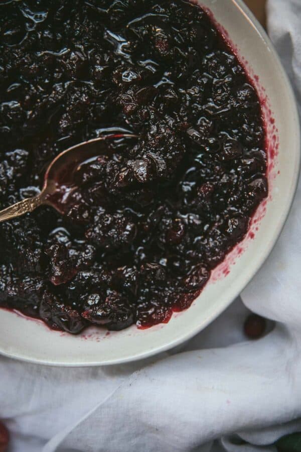 close up of simmered cranberries in a bowl with spoon