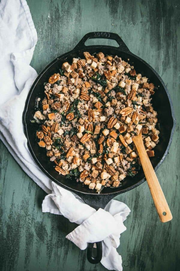 overhead of stuffing in a cast iron pan with white napkin on green background