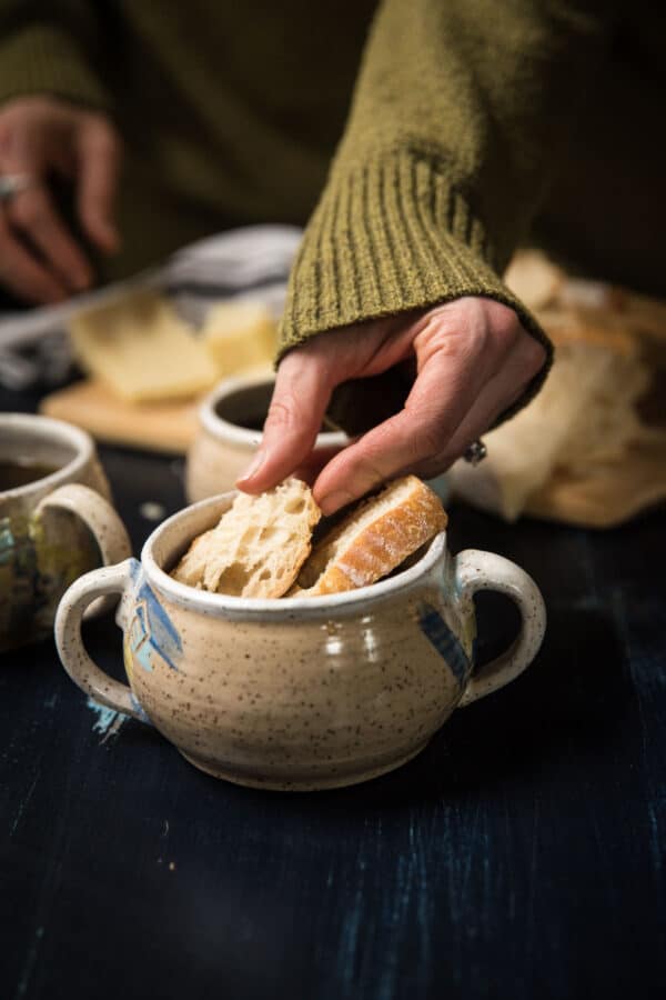 layering sliced of sourdough on top of soup