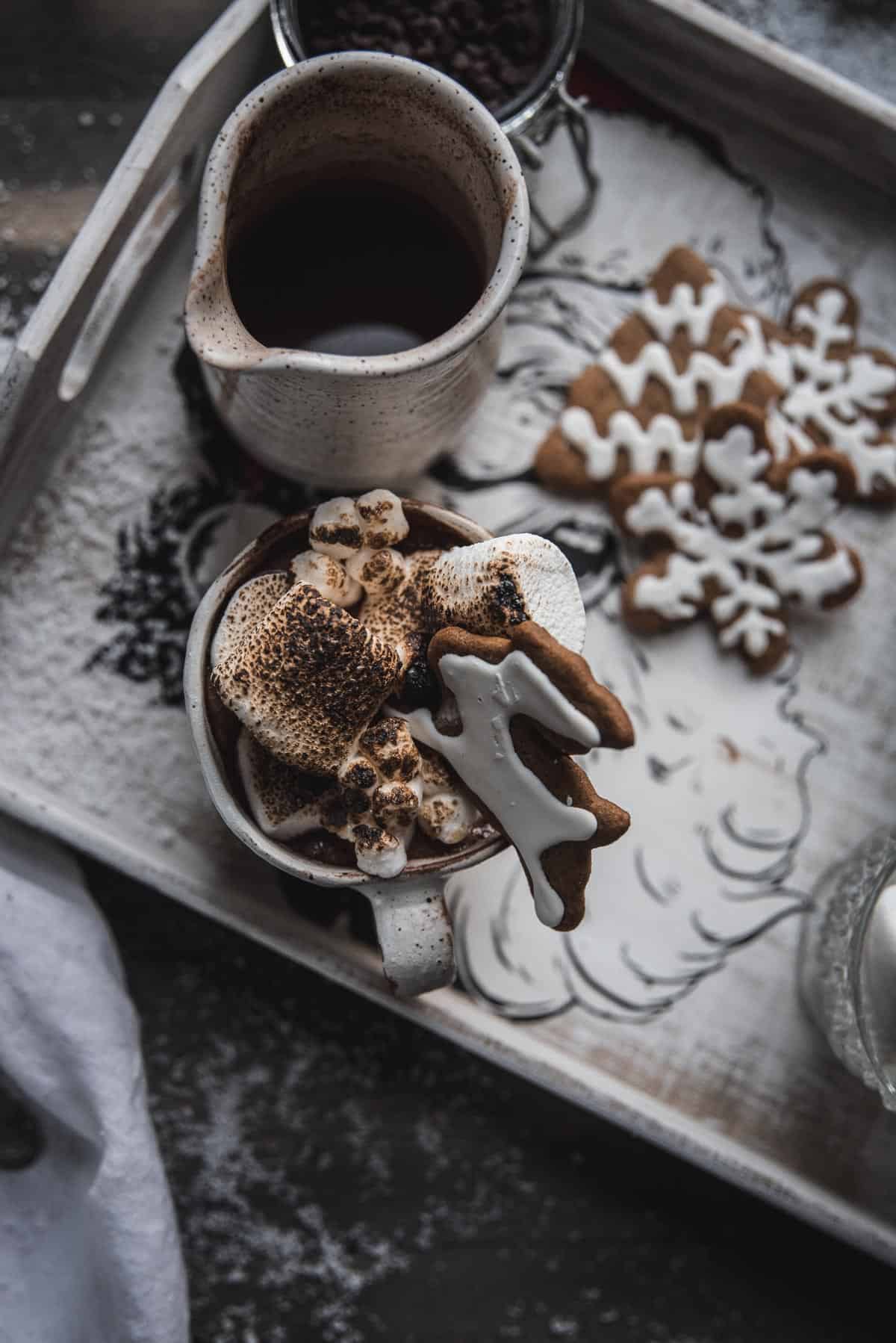 mug of hot chocolate topped with toasted marshmallows on a tray