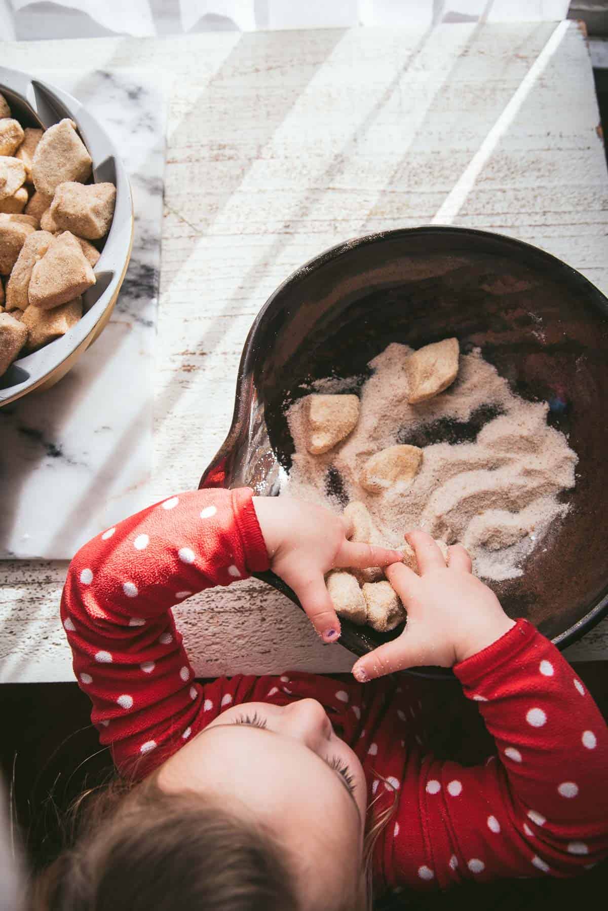 little kid putting sugared biscuits in a pan