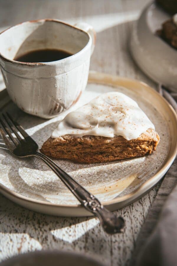 iced scone on a plate with a cup of coffee