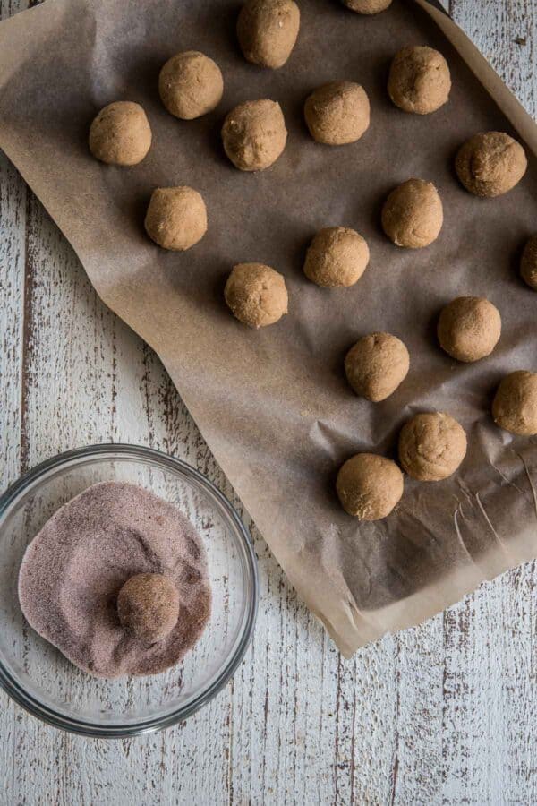 rolling cookies through cinnamon sugar