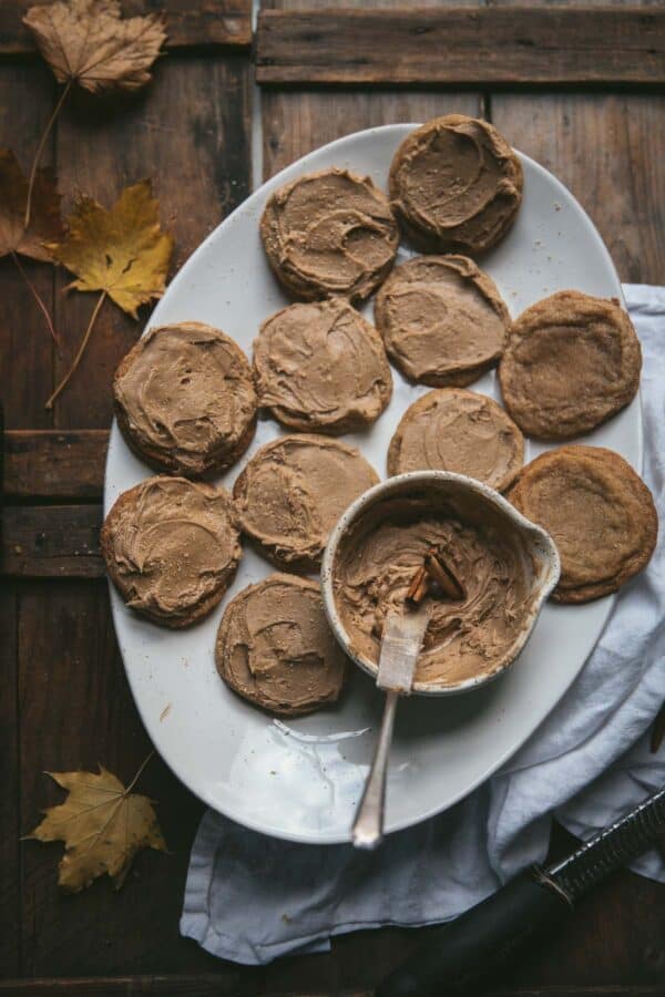 maple frosted cookies on a platter with bowl full of frosting