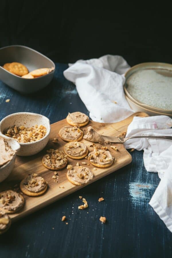 frosting ritz crackers on wooden cutting board