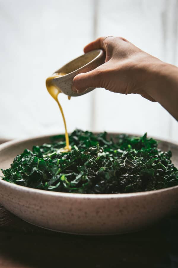 pouring dressing over chopped kale greens