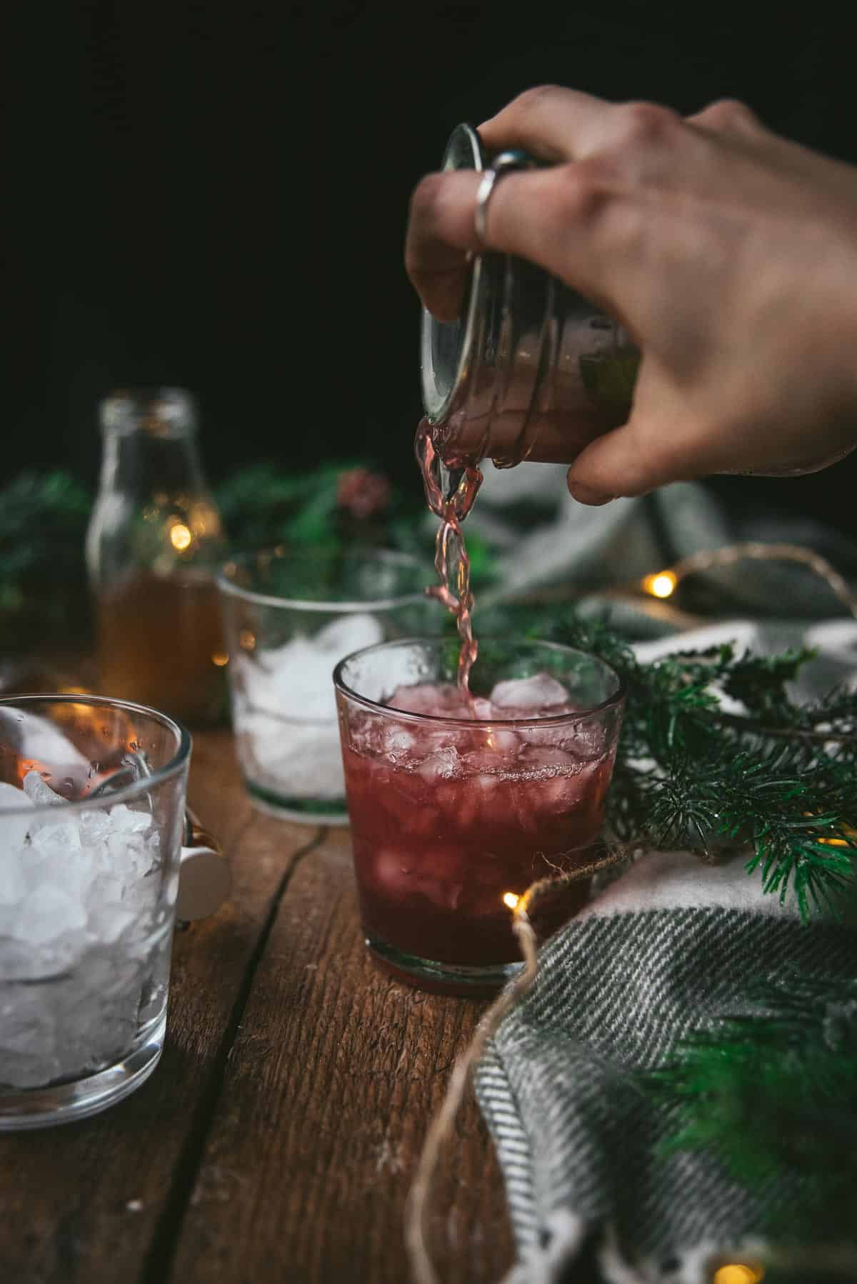 pouring cocktail over ice into a high ball glass