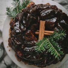 overhead of gooey monkey bread on a cake stand with cinnamon sticks and tree sprigs