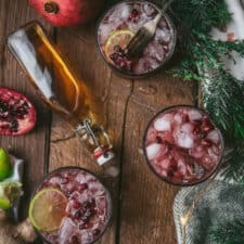 overhead of pomegranate cocktail in high ball with bourbon in a glass bottle