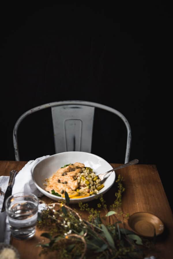 a chair next to a bowl of food on a wooden table