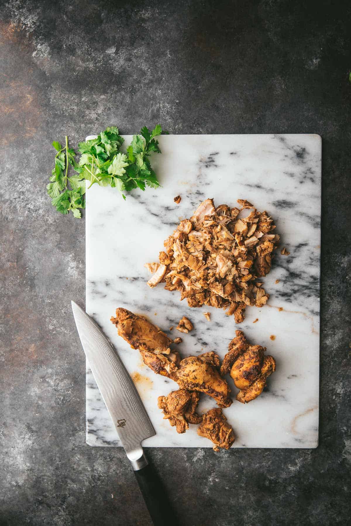 some chopped and some whole chicken thighs on a marble cutting board