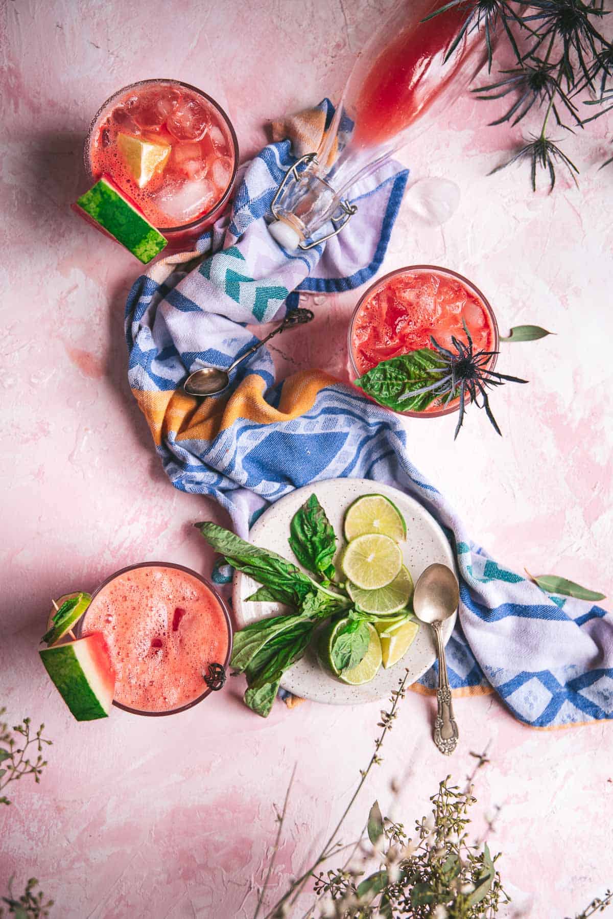 overhead of watermelon soda in classes on pink background with blue napkin