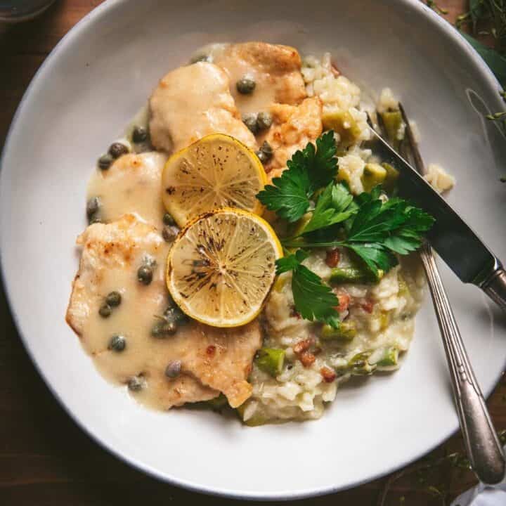 chicken with lemon and caper sauce in a plate over creamy asparagus risotto