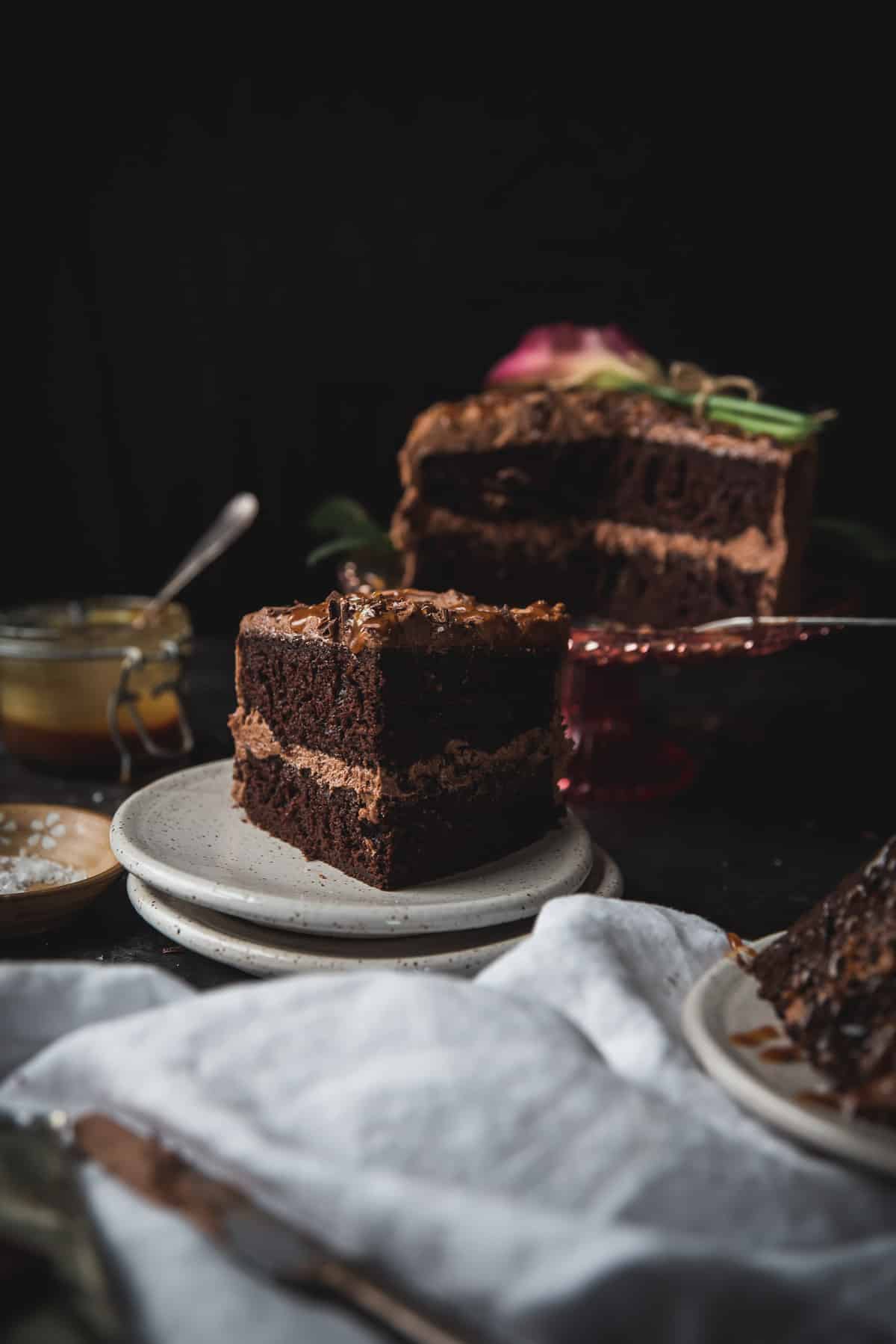 slice of chocolate layer cake on a plate with the cake in the background