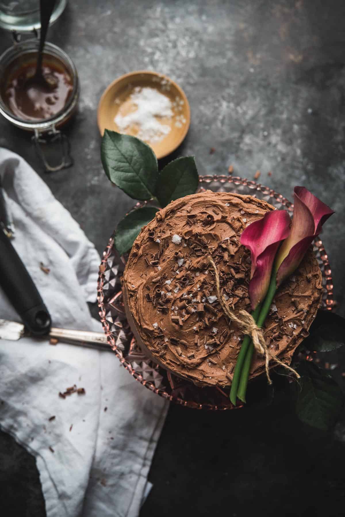 overhead shot of chocolate cake topped with flowers and chocolate shavings