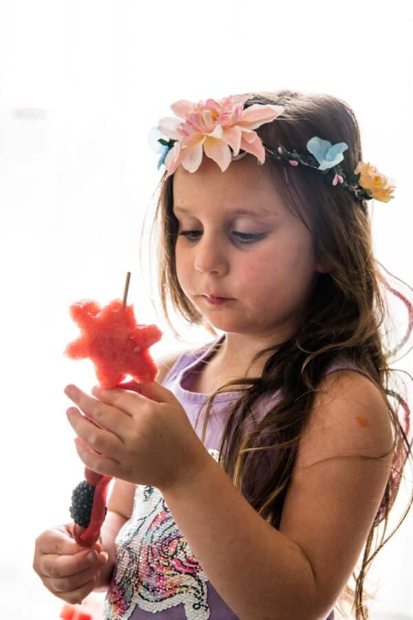 little girl with skewer of fruit