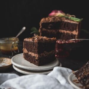 slice of chocolate layer cake on a plate with the cake in the background