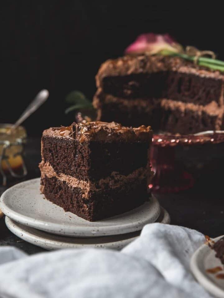 slice of chocolate layer cake on a plate with the cake in the background