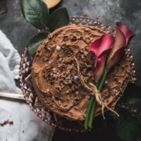 overhead shot of chocolate cake topped with flowers and chocolate shavings