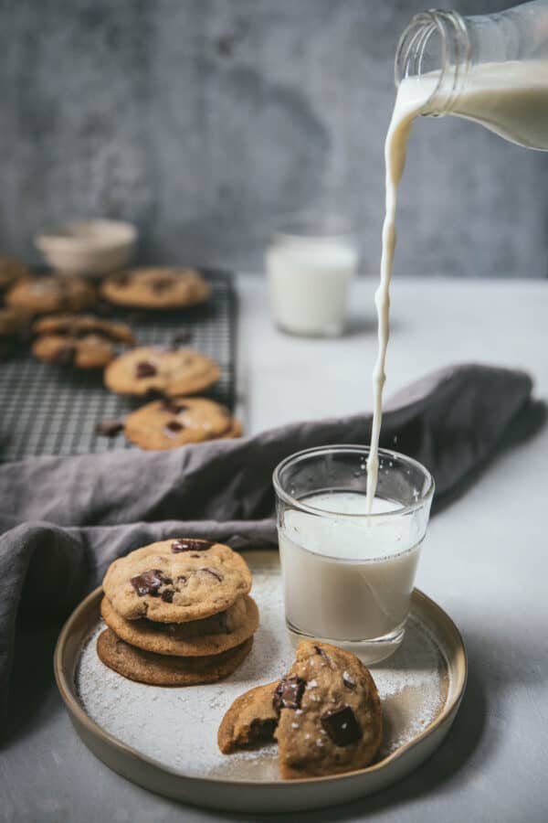 milk pouring into a cup next to a stack of cookies