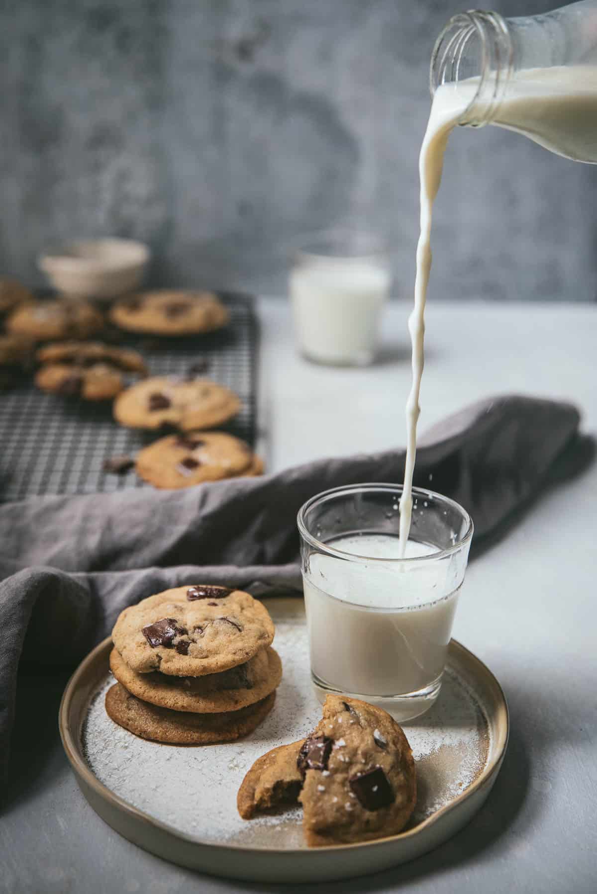 milk pouring into a cup next to a stack of cookies