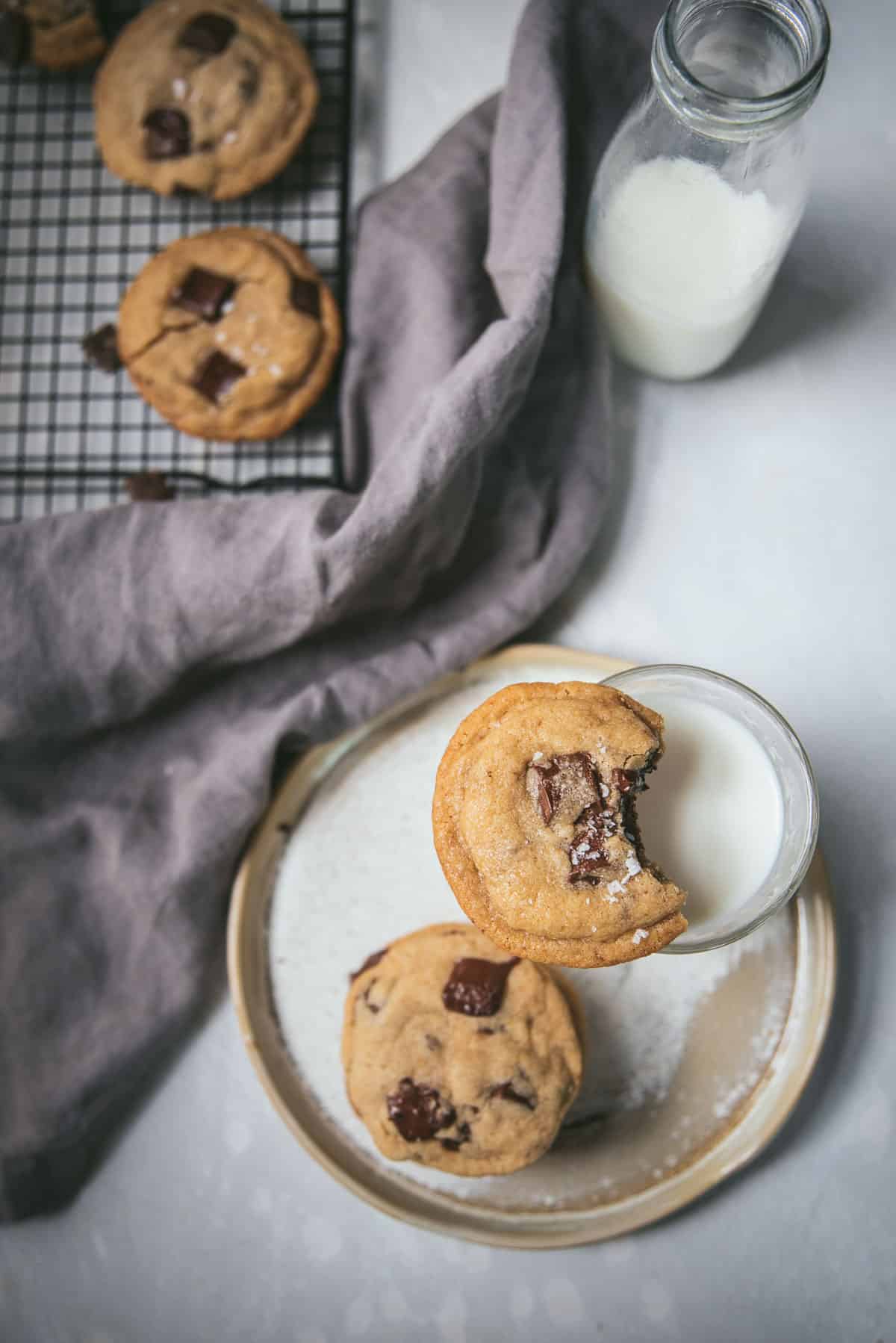 cookie balancing on a cup of milk with a bite taken out of it