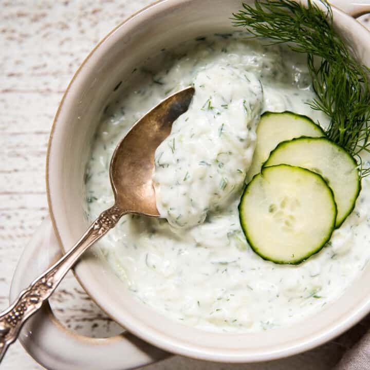 overhead of spoon scooping tzatziki out of a bowl