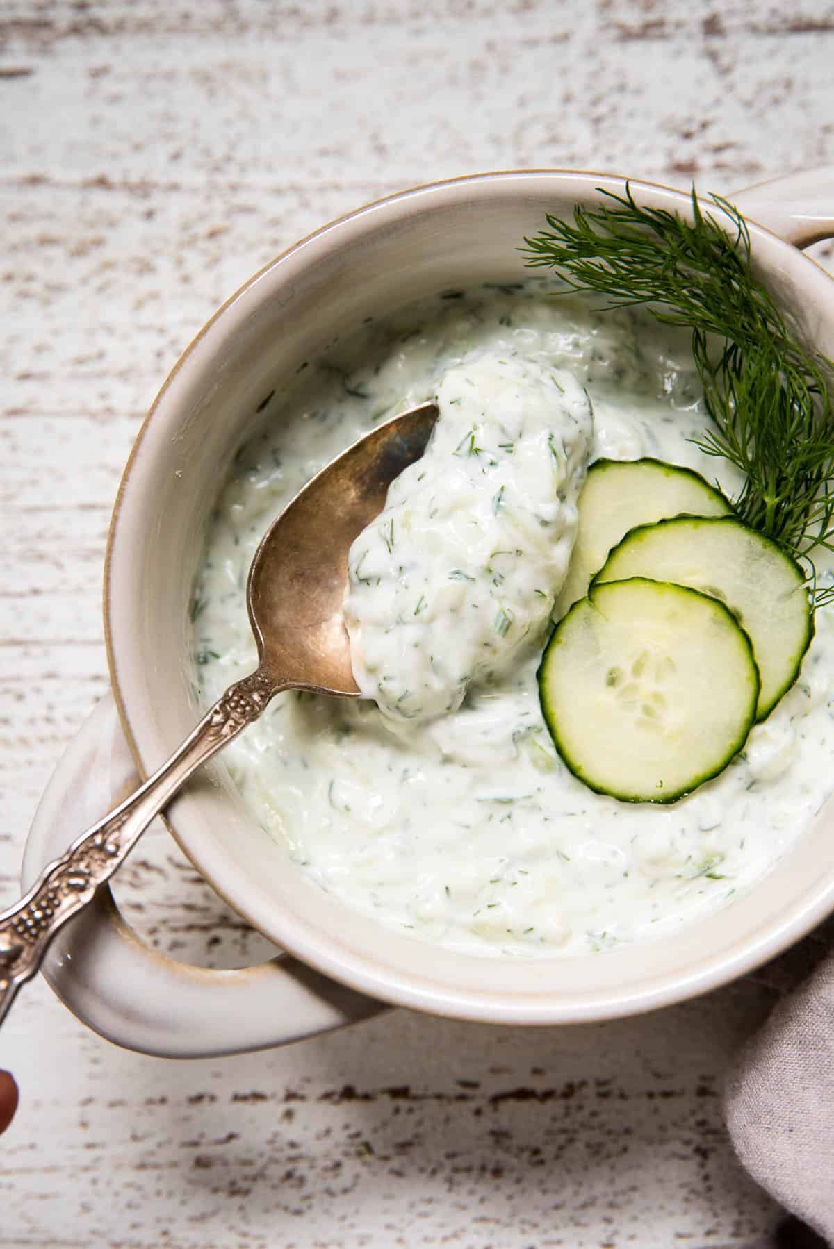 overhead of spoon scooping tzatziki out of a bowl