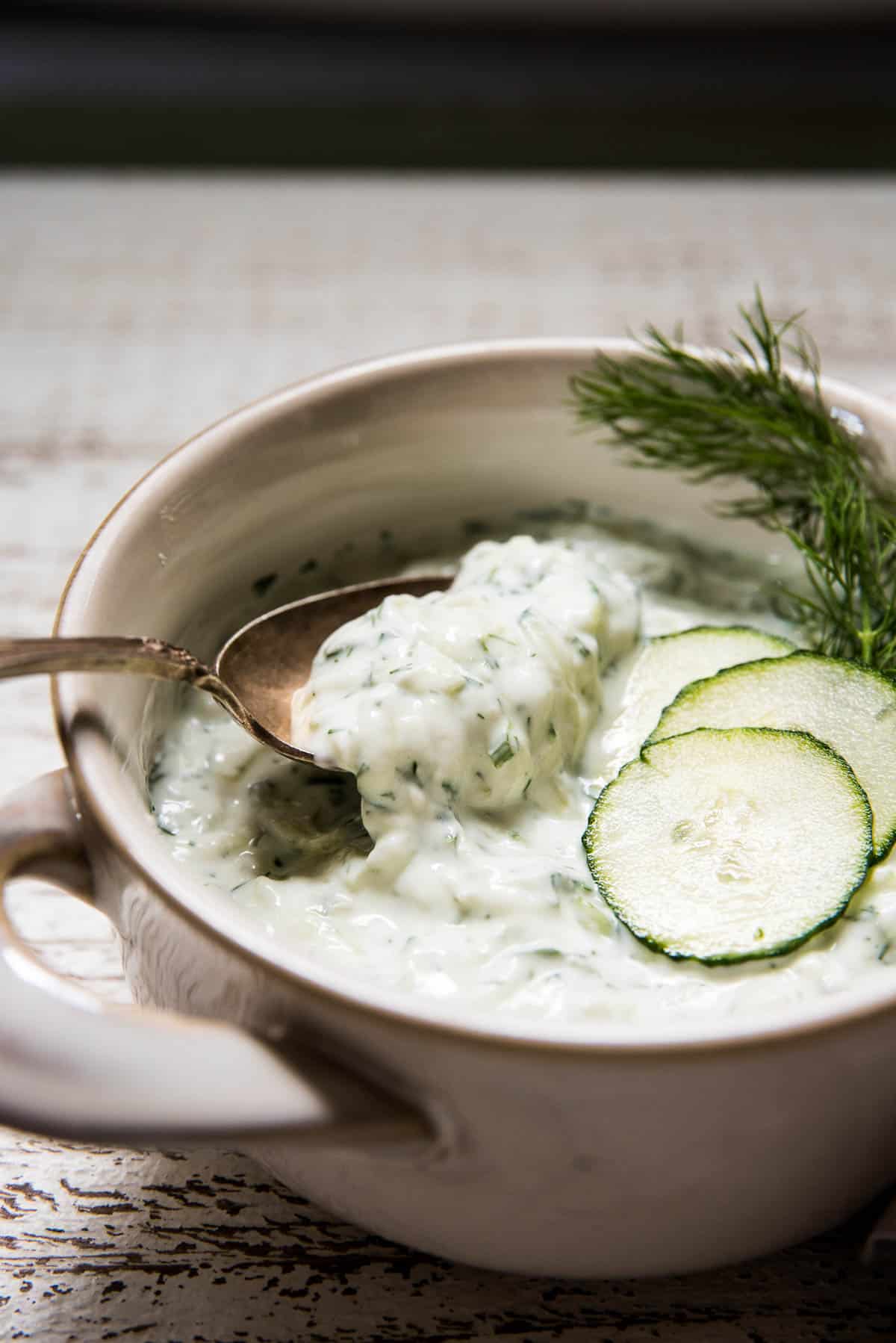 side angle of spoon scooping cucumber yogurt sauce