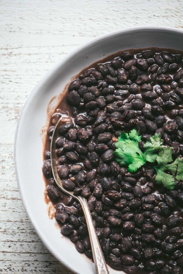 overhead of a spoon in a bowl of cooked black beans