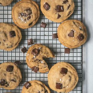 overhead of chocolate chip cookies on a baking rack with sea salt flakes in a bowl