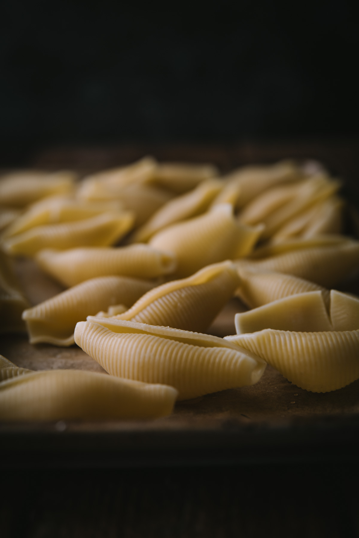Cooked jumbo pasta shells on a sheet tray to cool after they have been boiled.