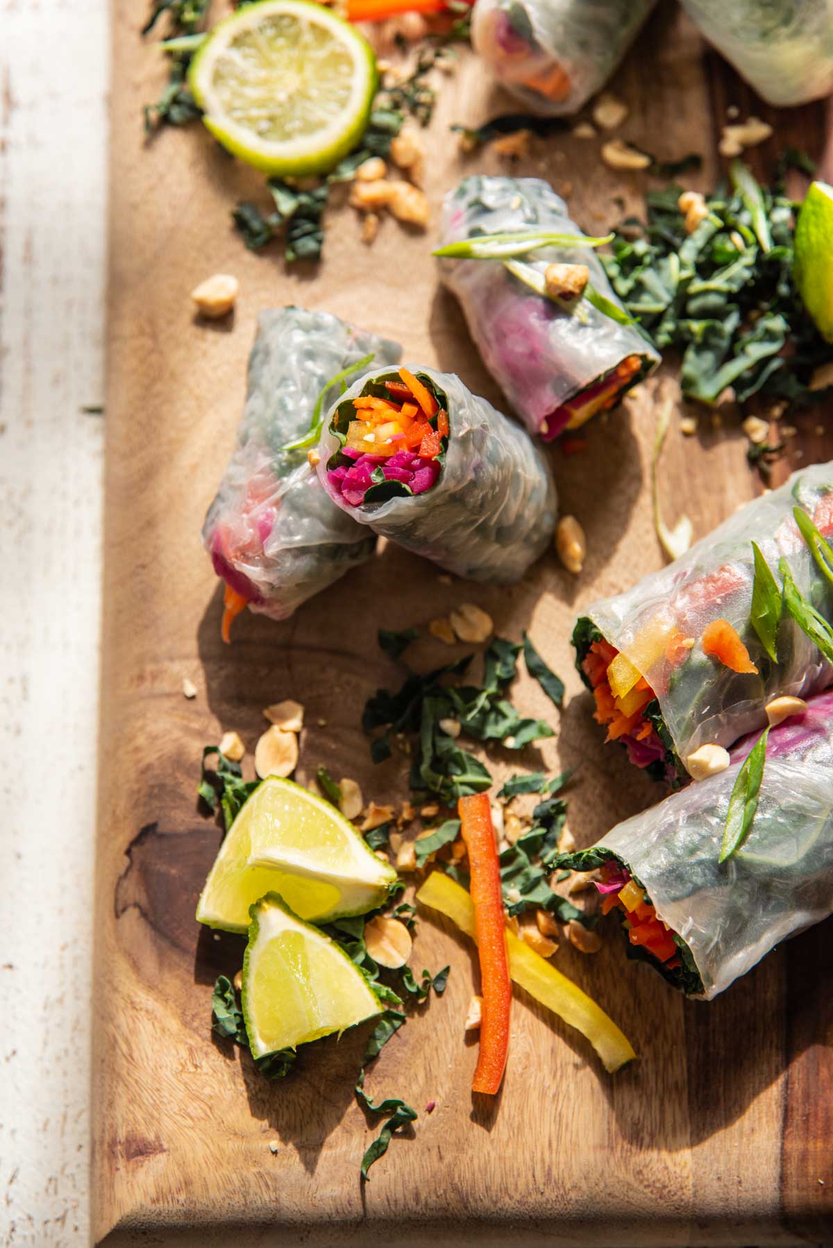 rainbow stuffed rice paper wrapped rolls on a wooden board